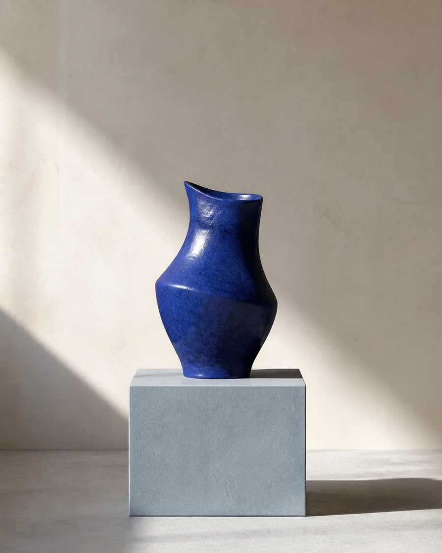 A sculptural cobalt blue ceramic vessel on a pale architectural plinth